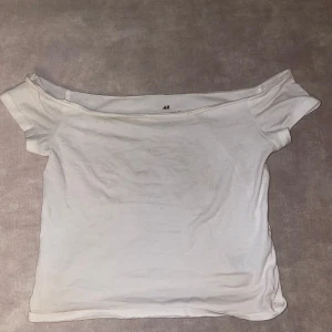 Vit offshoulder topp från H&M - Säljer en stilren vit offshoulder topp från H&M. Perfekt för en avslappnad look med korta ärmar och mjukt material. Passar bra till jeans eller kjol för en enkel och snygg outfit.