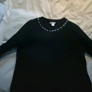 Svart tröja med pärldetaljer - (KAN BYTAS MOT EN VANLIG STICKAD TRÖJA) Svart stickad tröja med fina små pärl/diamant detaljer runt framsidan av halsen. Den är köpt second hand men annars ifrån H&M. Säljer pga att den ej används längre men jättefin! Pris går att diskuteras och kontakta för fler bilder!