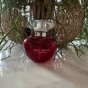 Säljer en elegant och feminin parfymflaska från Red Pearl. Flaskan är röd och har en rundad form med en genomskinlig kork. Perfekt för den som älskar en lyxig och sofistikerad doft. Passar både till vardags och speciella tillfällen.