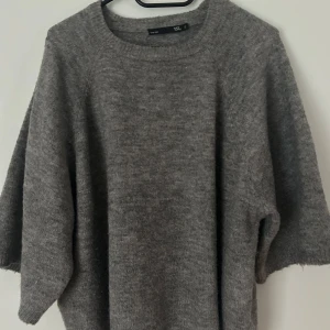 Tjocktröja med korta armar från lager - En grå skön stickad tröja. Den är i bra skick och har används ett förtal gånger då jag har många stickade tröjor.  