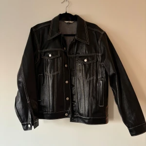 Eytys Black Denim Buck Tar Jacket - Lackad jeansjacka från Eytys i unisexmodell. Normal i storleken. Storlek L för kvinna och M för man. Använd fåtal gånger så väldigt fint skick. Nypris: 3300 kr.  1/2 axlar: 50 cm 1/2 under armhåla: 58 cm Armlängd: 61 cm 