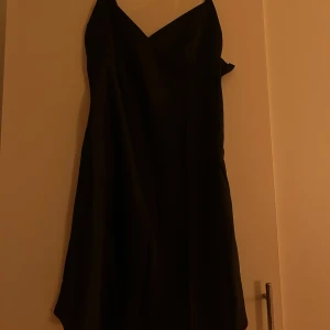 Svart klänning - En klänning i satin-imitation från H&M i storlek S med smala axelband och dragkedja. Aldrig använd och lappen kvar. 