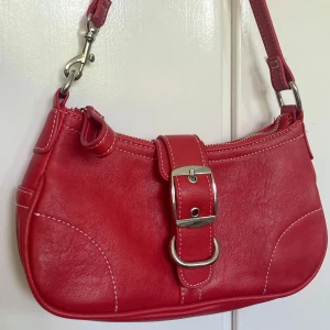 Röd handväska  - Säljer en skitsnygg trendig röd handväska med en cool spänndetalj på framsidan. Den är i perfekt skick (inga defekter/slitage)❤️Kontakta mig om du vill ha fler bilder🫶🏼