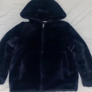Blå teddyjacka med huva - Mysig blå vinterjacka med huva och dragkedja framtill. Perfekt nu i vinter när du vill hålla dig varm.