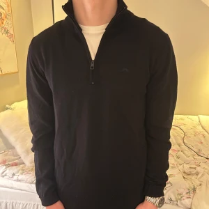 Mörkblå halfzip från J.Lindeberg - Snygg mörkblå tröja från J.Lindeberg med halv dragkedja. Perfekt för en stilren look, oavsett tillfälle. Tröjan är i storlek S och har en klassisk passform. Hör av dig vid frågor!