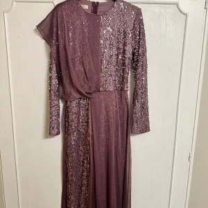 Lila glittrig jumpsuit - Säljer denna fina lila långärmade festjumpsuit med glittrande paljetter. Den har bara används 1 gång och är i mycket bra skick.