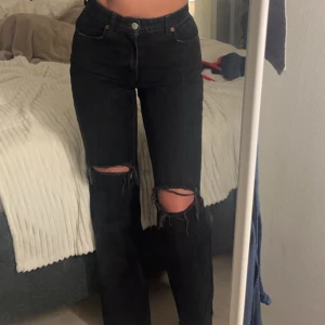 Svarta jeans från ZARA - Snygga svarta jeans med hög midja och slitningar på knäna. Passformen är straight och materialet är klassiskt denim. 
