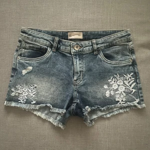 Jeansshorts med broderi - Jeansshorts med fransiga kanter och blommigt broderi. Storlek 164 men passar även xs. Knappt använda. 