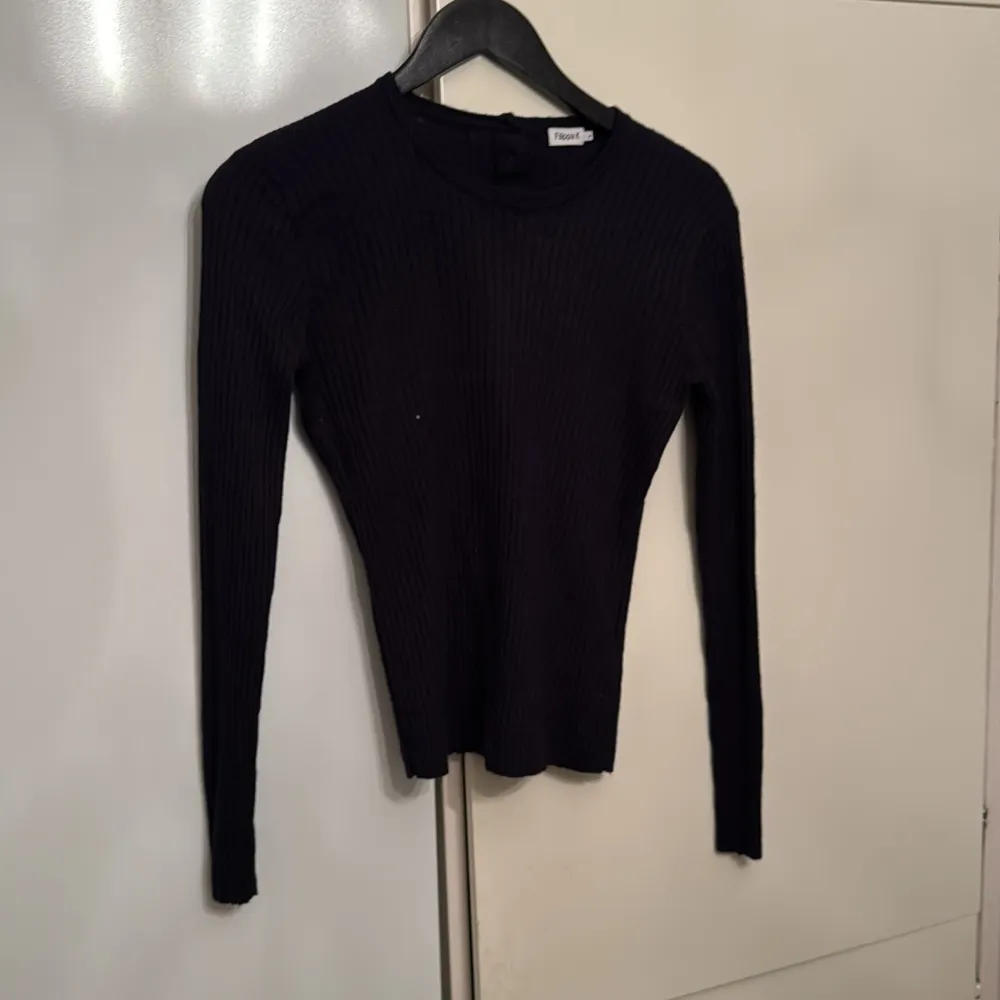 Säljer en stilren svart ribbad tröja från Filippa K. Tröjan har en klassisk design med långa ärmar och rund halsringning. Perfekt för en minimalistisk garderob.. Neuletakit & Villapaidat.