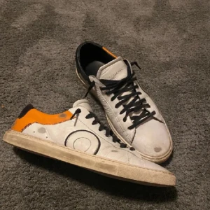 Oliver cabells skor - Snygga vita sneakers med svarta snören och coola orange detaljer. Perfekta för en avslappnad stil med en unik touch. Skorna har en rund tå och en bekväm passform.