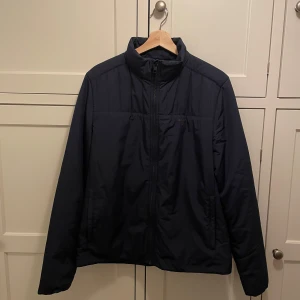 Gant mörkblå dunjacka, storlek M – Jättefint skick - •	Storlek: M 	•	Färg: Mörkblå 	•	Material: Dunfylld för värme och komfort 	•	Skick: Utmärkt  En stilren och klassisk dunjacka som passar till allt. Perfekt för både vardag och mer uppklädda tillfällen. Hög kvalitet och tidlös design gör detta till ett mångsidigt plagg i garderoben. Fraktar samma dag köpet genomförs. Skriv vid frågor!