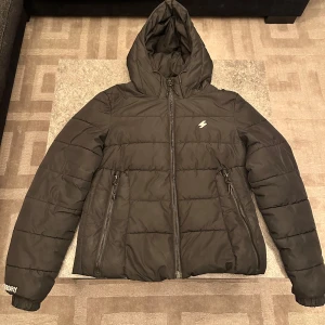 Svart pufferjacka från Superdry - Säljer en svart pufferjacka från Superdry med huva och dragkedja. Skick 8/10. Priset kan diskuteras