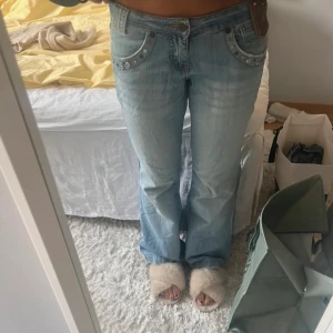 Ljusblå jeans med detaljer - Snygga ljusblå jeans från Vintage denim med unika detaljer som nitar och stjärnor vid fickorna. De har en bootcut-stil och är lågmidjade. 
