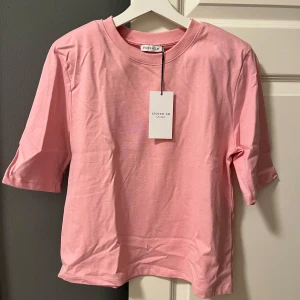 Rosa t-shirt från Stockholm - Snygg rosa t-shirt från Stockholm med korta ärmar och med avtagbara axel puffar. Nypris 399🩷