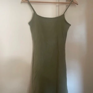 Olivgrön klänning från H&M Divided - Säljer en stilren olivgrön klänning från H&M Divided. Klänningen har smala axelband och en enkel design som passar perfekt för varma dagar.