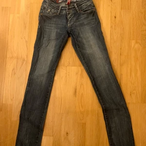 Low waist jeans - Snygga blå jeans med broderade detaljer på bakfickorna och en klassisk femficksdesign. De har en normal passform och är perfekta för en avslappnad stil. Jeansen har en dragkedja och knappar framtill.