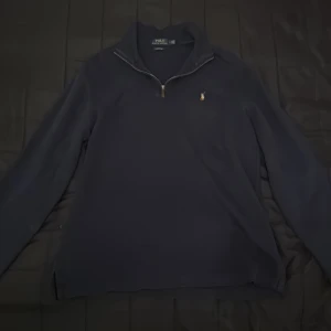 Mörkblå half zip från Polo Ralph Lauren - Säljer en stilren mörkblå tröja från Polo Ralph Lauren med dragkedja vid halsen och det klassiska broderade logotypen på bröstet. Perfekt för en avslappnad men ändå elegant stil. Fantastisk nu mot vintern!!
