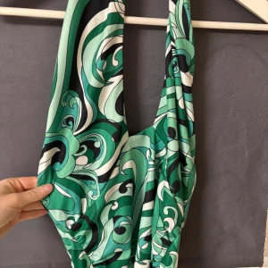 Grön mönstrad klänning från BikBok - Snygg grön klänning från BikBok med ett unikt mönster i svart och vitt. Klänningen har en halterneck-design och är perfekt för en somrig look. Materialet är mjukt och följsamt.