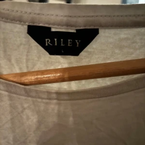 Vit t-shirt från Riley - Säljer en klassisk vit t-shirt från Riley i storlek L. T-shirten är tillverkad i mjuk bomull med en liten andel elastan för extra komfort. Perfekt basplagg för alla tillfällen. Gjord av bomull. 