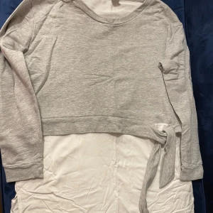 Grå tröja med knyt från Lindex - Säljer en stilren grå tröja från Lindex i storlek M. Tröjan har långa ärmar och en snygg knytning i sidan som ger en extra touch. Perfekt för en avslappnad look.