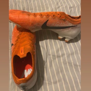  nike mercurial vapor 360 orange vita - Snygga fotbollsskor från Nike i en iögonfallande orange och vit färgkombination. Skorna har en svart Nike-logga på sidan och är designade för optimalt grepp och kontroll på planen. Mycket svåra att på tag på 