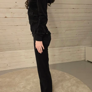Svart juicy set - Snygga svarta juicy velourbyxor och juicy hoddie med normal passform.  Byxorna har fickor bak med knappdetaljer. Är välskötta och har passform och utseende som om de vore nya. Personen på bilden är 166 och har str xxs.