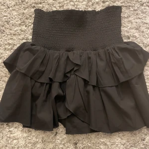 Svart neo noir kjol med volang - Trendig svart kjol med volangdetaljer och en elastisk midja för bekväm passform. Sparsamt använd och inga defekter eller liknande.