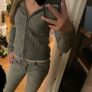 Grå ribbad hoodie från 157 - Säljer en grå ribbad hoodie från 157 med dragkedja och huva. Perfekt för en avslappnad stil. Tröjan har långa ärmar och en bekväm passform.