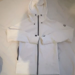 Vit vindjacka med huva oanvänd från MONCLER  - Snygg vit jacka med huva och dragkedja framtill. Säljer pågrund av fel storlek och sen tappade jag bort retur blanketten i flytt  