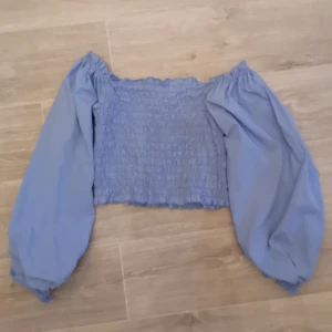 Blå offshoulder topp från Bik Bok - Säljer en blå offshoulder topp från Bik Bok med smockdetaljer och långa puffärmar💙. Perfekt för en stilren look. Säljer den då jag bara har använt den ett fåtal gånger