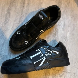 Svarta sneakers från Valentino - Snygga svarta sneakers från Valentino.  Skorna har en stilren design och har använts ett få par gånger. I storlek 43 (kommer med skosnören)