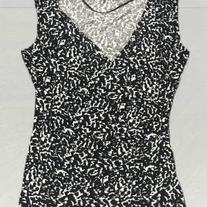 Svartvit mönstrad ärmlös topp - Snygg ärmlös topp med svartvitt abstrakt mönster och v-ringad hals. Perfekt för en stilren look.