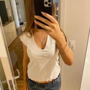 Vit topp från Zara - Säljer en vit topp från Zara med v-ringning och korta ärmar. Notera att tröjan har slitningar vid sömmar för att den är så på modellen💕