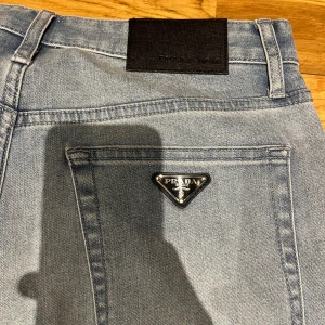 Blå jeans från Prada - Snygga blå jeans från Prada med klassisk femficksdesign och en diskret logotyp på bakfickan. Jeansen passar tight. Slim fit