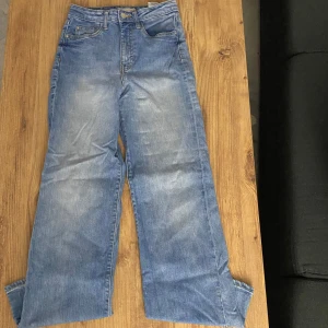 Blå jeans med hög midja - Snygga blå jeans med hög midja och en avslappnad passform. Perfekta för en casual look. De har en klassisk design med fem fickor och knappgylf. Wide jeans.