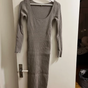 Beige ribbad klänning - Snygg beige ribbad klänning med lång ärm och rund halsringning. Perfekt för en stilren look. Klänningen är figurnära och sträcker sig ner till knäna.