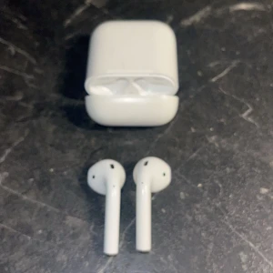 Vita trådlösa hörlurar med laddningsetui - Säljer ett par vita trådlösa hörlurar med tillhörande laddningsetui. Perfekta för musik och samtal på språng. Smidig och kompakt design som enkelt får plats i fickan.