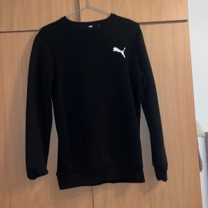 Svart tröja från Puma - Säljer en stilren svart tröja från Puma med deras ikoniska logga på bröstet. Tröjan har långa ärmar och en klassisk passform. Perfekt för en avslappnad look.