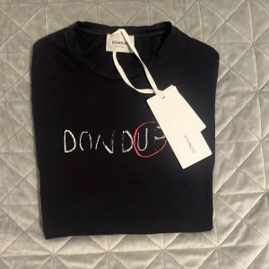 Dondup t-shirt   - Snygg svart t-shirt från Dondup med ett coolt broderat märke på framsidan. Tillverkad i Italien, perfekt för en stilren look. T-shirten har en klassisk passform och är kortärmad. Den är 10/10 skick och og medföljer! FAST PRIS!