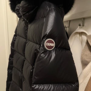 Svart dunjacka från Colmar - Svart glansig dunjacka från Colmar med en äkta pälskrage som går att ta av. En varm vinterjacka i mycket bra skick. . Nypris 7.500:-
