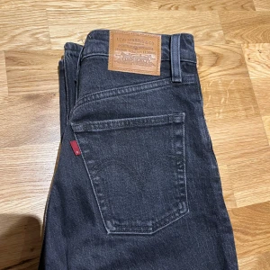 Svarta jeans från Levi's - Snygga svarta Levi's jeans i modellen Ribcage Straight Ankle. De har en hög midja och raka ben, vilket ger en klassisk look. Sparsamt använda 