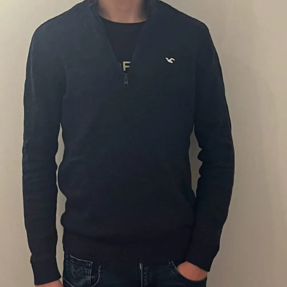 Säljer en snygg mörkblå tröja från Hollister med dragkedja vid halsen. Tröjan har långa ärmar och en liten logga på bröstet. Perfekt för en stilren look. Skriv om du har funderingar och priset är inte hugget i sten!. Neuletakit & Villapaidat.