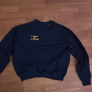 Mörkblå sweatshirt med tryck - Säljer en mörkblå sweatshirt med gul text på bröstet. Tröjan har långa ärmar och en rund halsringning. Perfekt för en avslappnad stil. Nypris på den här är 529kr. 