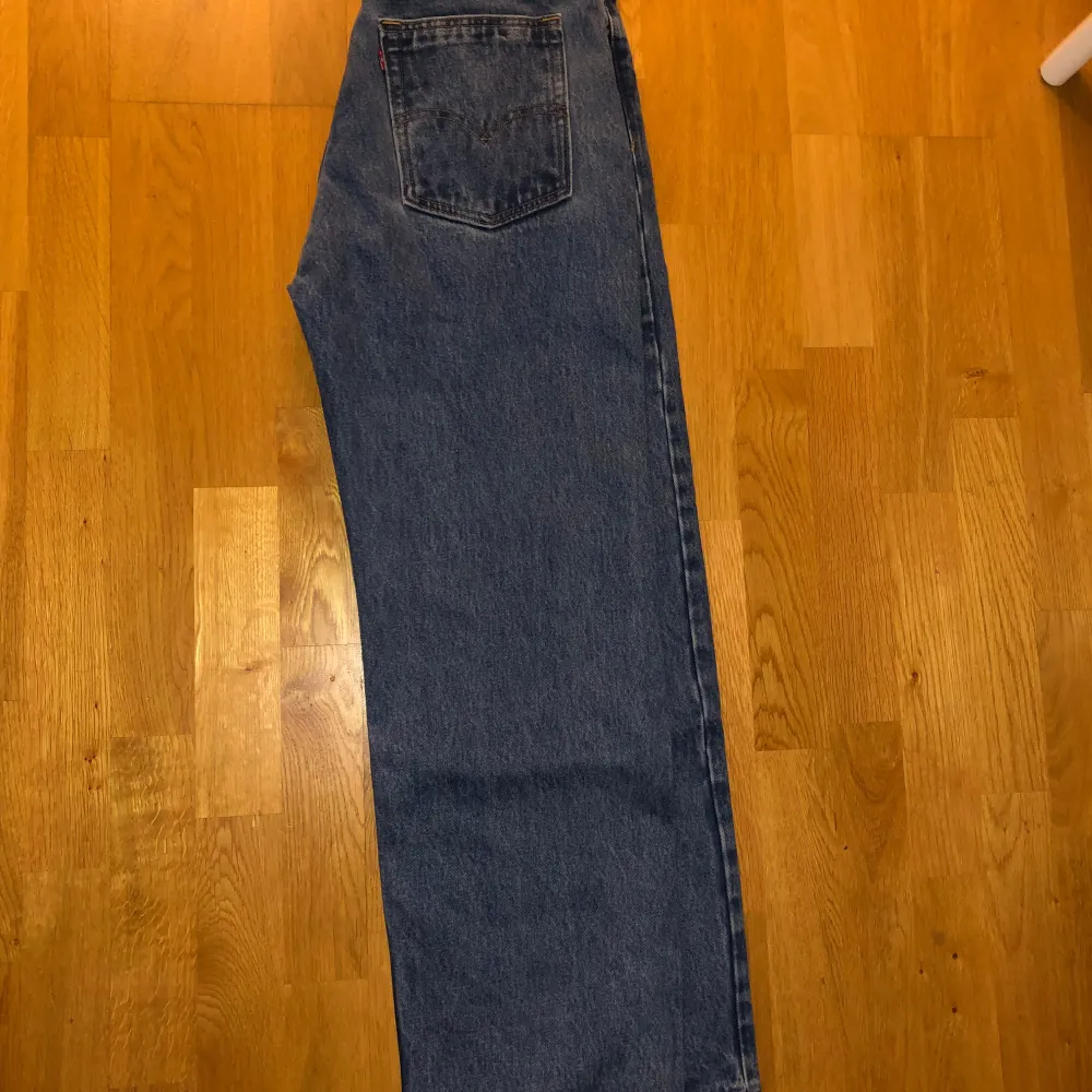 Säljer ett par klassiska blå baggy jeans från Levi's. De har en avslappnad passform med hög midja och är tillverkade i slitstarkt denim. Perfekta för en casual look. Märkeslappen och Levi's logga syns tydligt på baksidan.. Farkut & Housut.