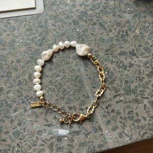 Guldarmband med äkta pärlor - Huldigt armband med äkta vita pärlor och guldfärgad kedja. Armbandet har en mix av oregelbundna pärlor och en guldkedja. Aldrig använd.