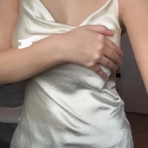 Vit sidenklänning från Gina Tricot - Elegant vit klänning i siden från Gina Tricot. Klänningen har en v-ringad design och är ärmlös, vilket ger en stilren och sofistikerad look. Perfekt för speciella tillfällen.