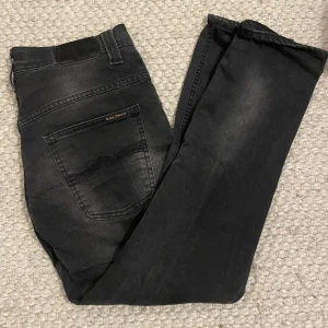 Svarta jeans från Nudie Jeans - Snygga svarta jeans från Nudie Jeans i en klassisk stil. De har en rak passform och är tillverkade i ett slitstarkt material. Perfekta för en stilren look. Strl 31/32 men rätt så korta. Pris kan diskuteras 