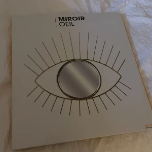 Dekorativ spegel i form av ett öga - Snygg och unik spegel från Kiosque formad som ett öga med strålande detaljer runtom. Perfekt för att ge en modern touch till ditt hem. Spegeln har en guldig ram och är både stilren och iögonfallande.💗