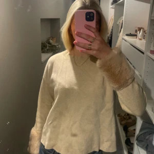 Beige tröja med pälsdetaljer - Säljer en stilren beige tröja med långa ärmar och pälsdetaljer vid ärmsluten.🥰🥰