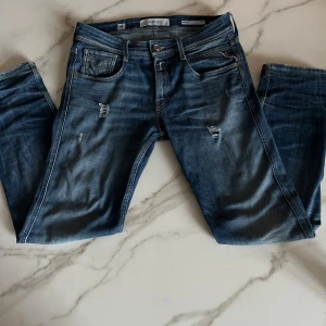 Replay anbass - Blåa replay anbass jeans med slitningar sjukt snygg färgblandning. Skicket är 7,5/10 pågrund av defekten på sista bilden! Och storleken är 28:30 men kan passa lite större